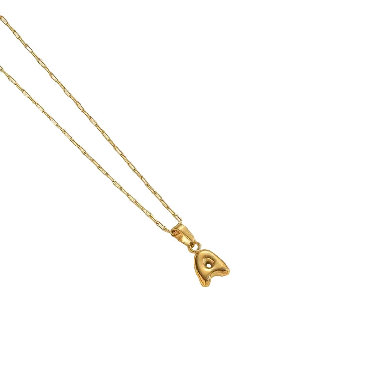 Gold necklace with a heart-shaped pendant on a light beige background